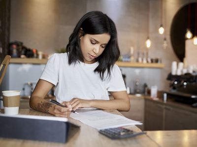 Female cafe owner signing papers calculating business expenses