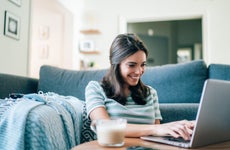 A smiling young woman looks at her laptop